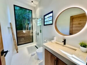 Baño moderno con ducha acristalada y espejo redondo iluminado