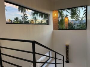 Escalera interior con ventanales hacia las palmeras