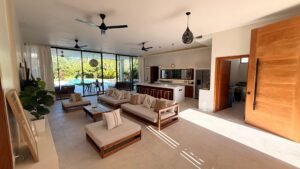 Salón con cocina abierta y ventanales hacia la piscina